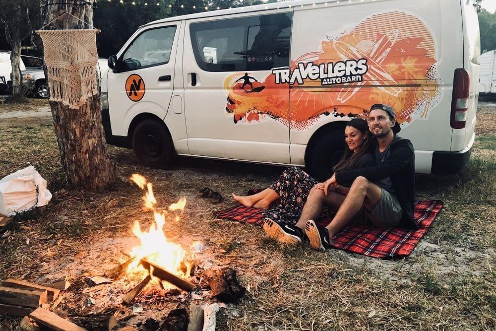 Pärchen am Lagerfeuer sitzend vor einem Travellers Autobarn Camper